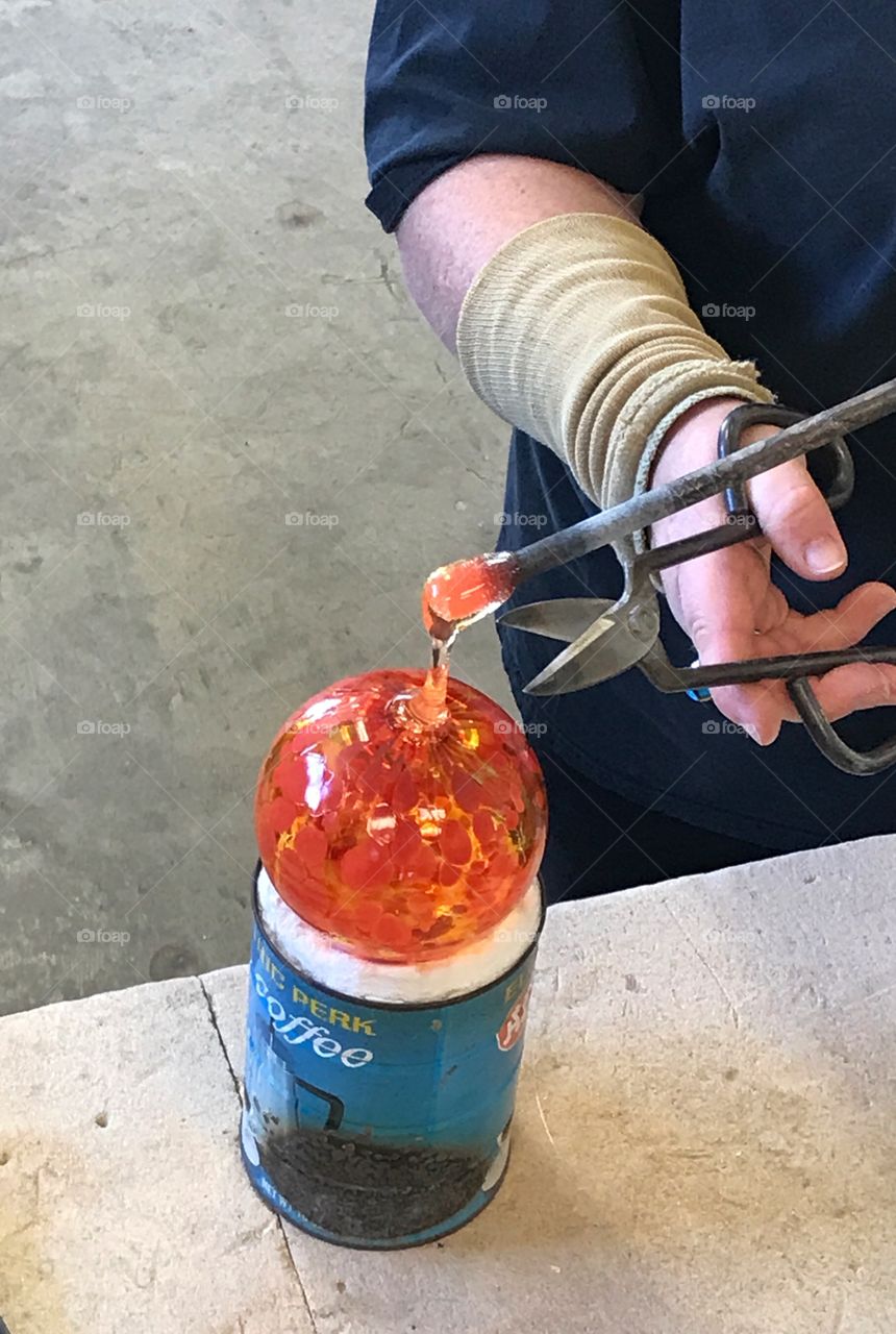 Glass artist making orange glass ornament 