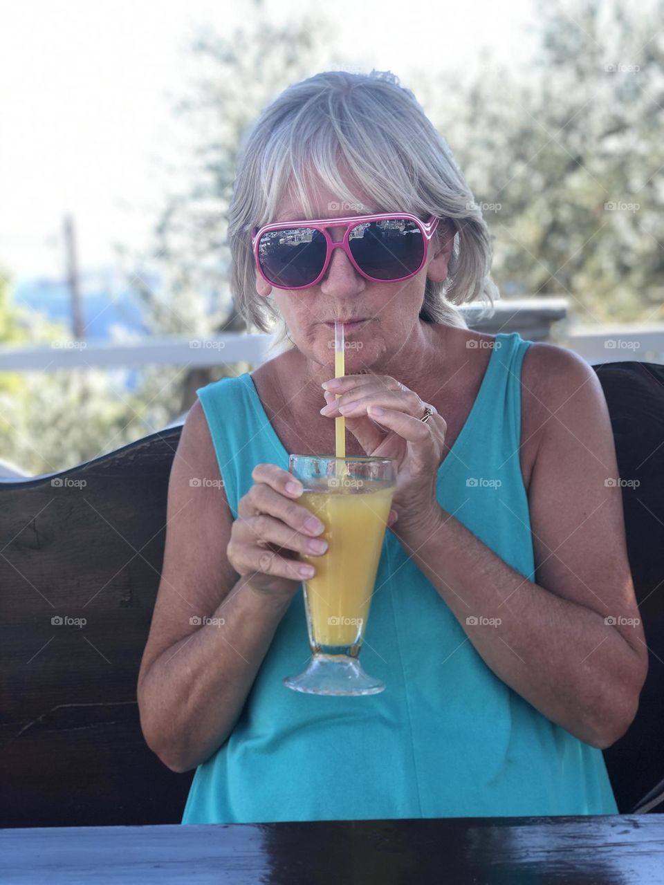 Female wearing sunglasses, holding a glass of fresh orange juice, drink, smiling, happy