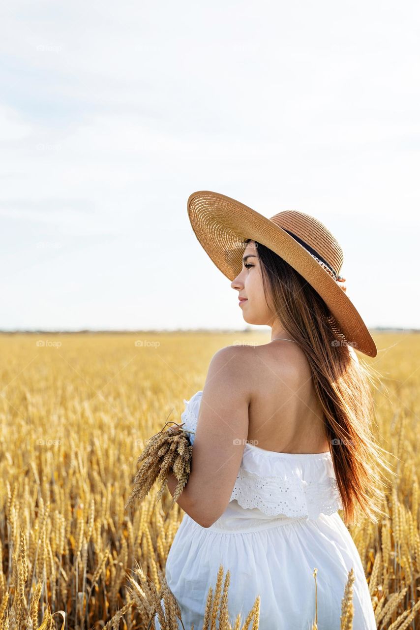 young woman in straw hat in wheat field