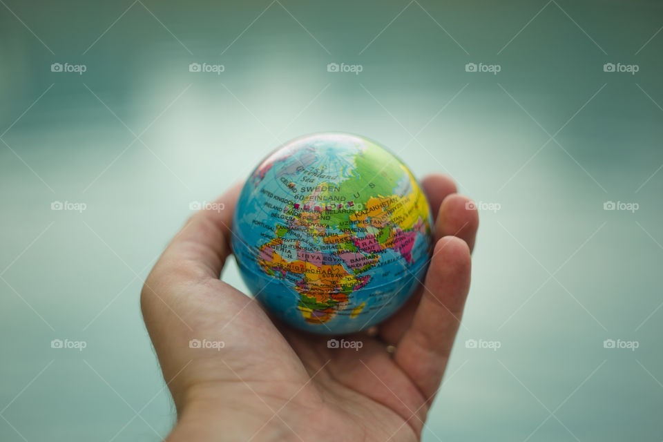 hand holding world sphere, showing Africa, Europe and Asia continents