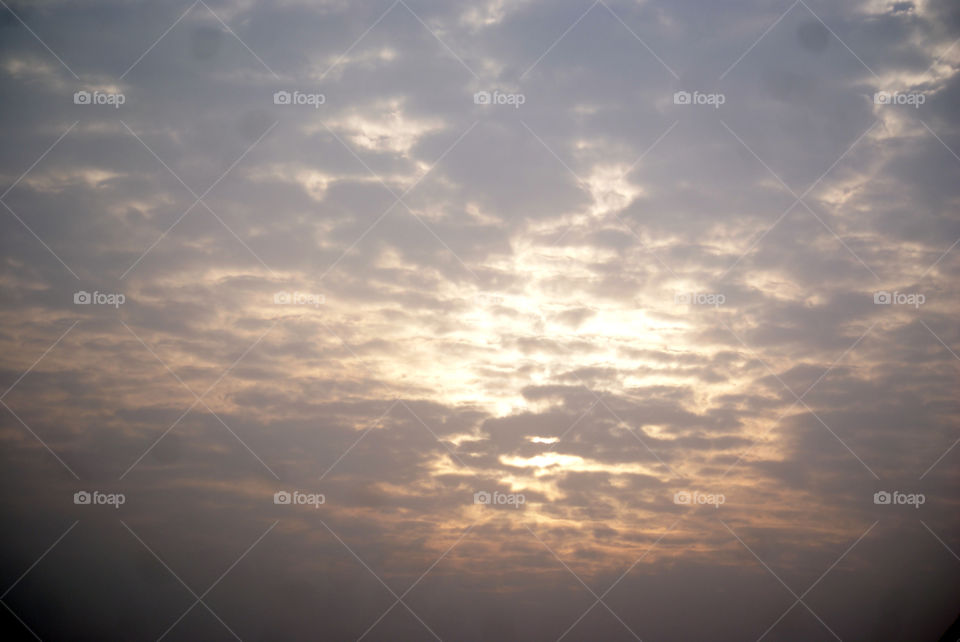 Cloudy sky hiding the sun beneath it, like a game of peek a boo.