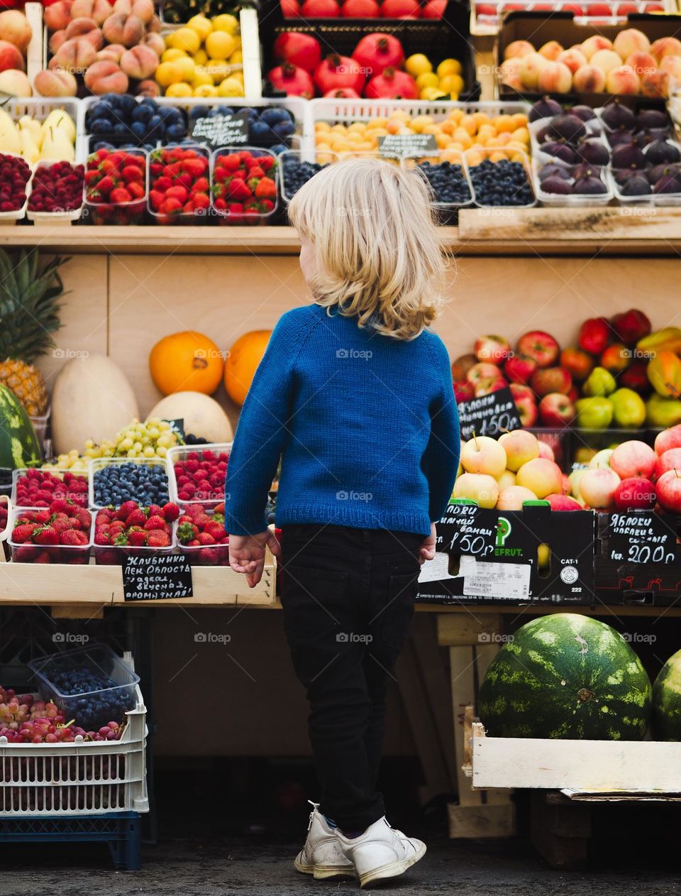 Cute little boy with blonde hair wearing blue sweater on market, portrait of child 