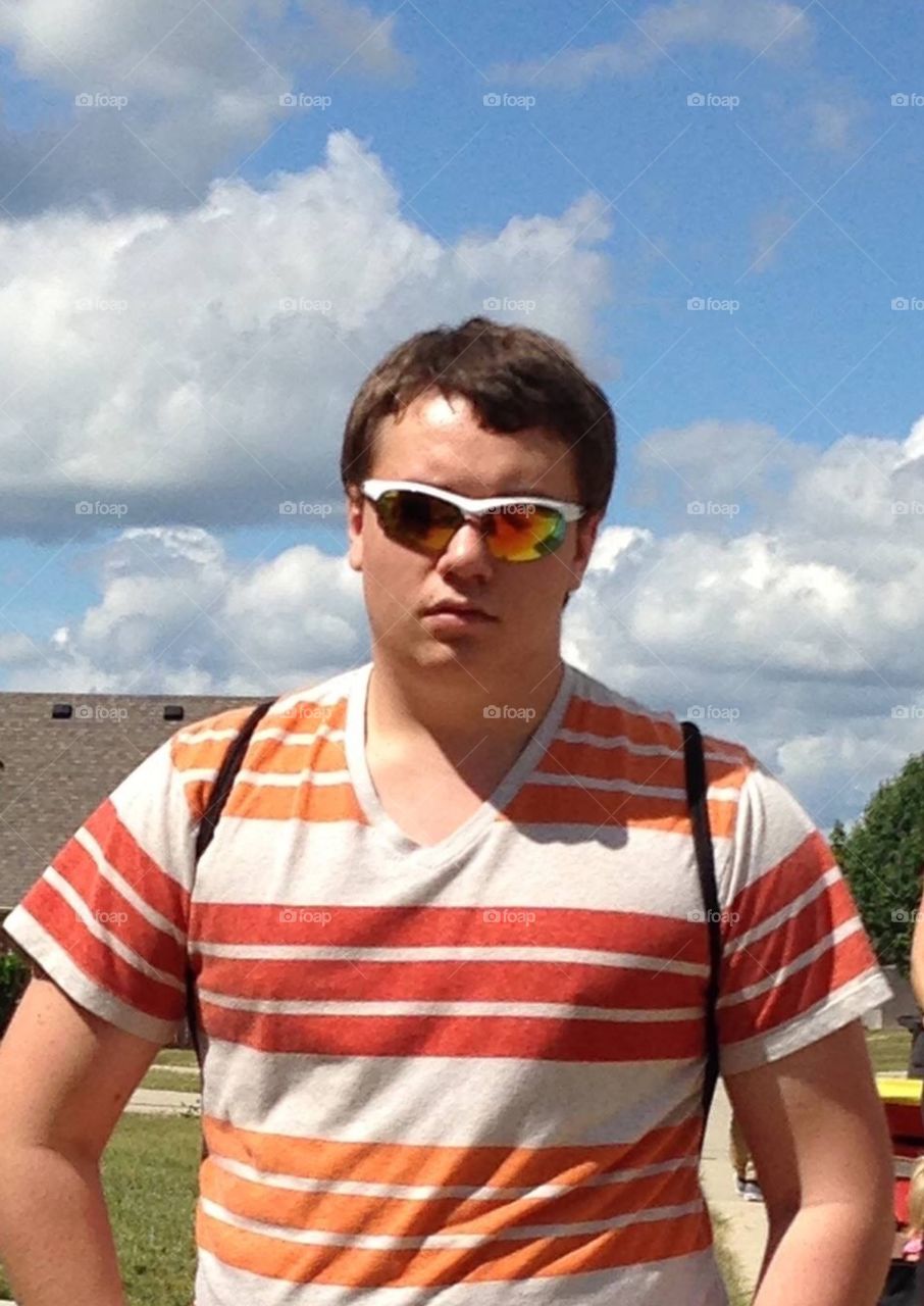 Portrait of man wearing sunglasses against cloudy sky