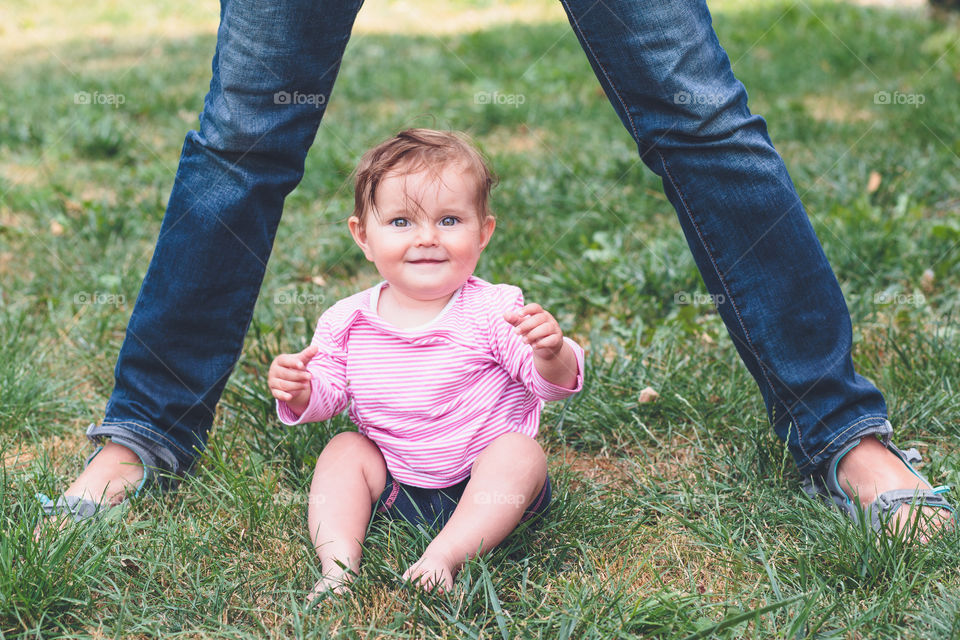 Little girl sitting on grass between father's legs