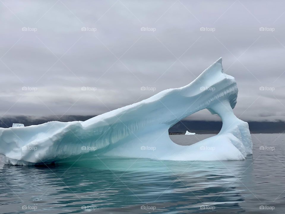 A view of an iceberg thru a hole in another iceberg