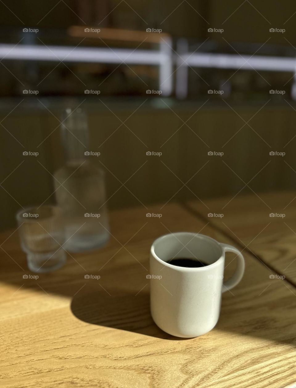 Coffee cup at the table on the edge of light and shadow 