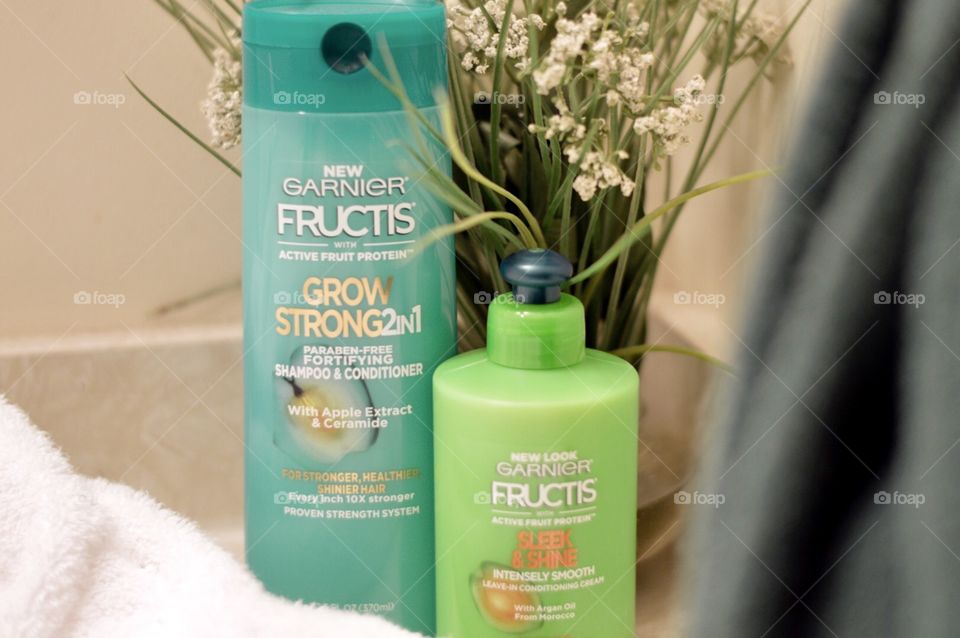 Garnier in one shampoo and conditioner and anti-frizz on a bathroom countertop with a white towel