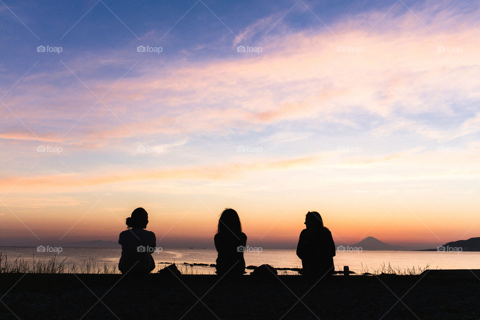 Three friends enjoying sunset by the ocean 
