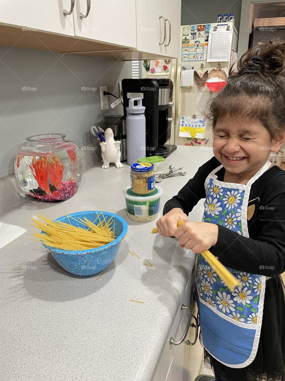 Little girl helps Mommy in kitchen, breaking pasta for cooking, helping mommy cook pasta 