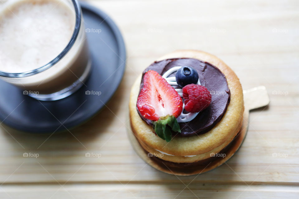 Cake with berries and cappuccino on wooden table. Good morning!