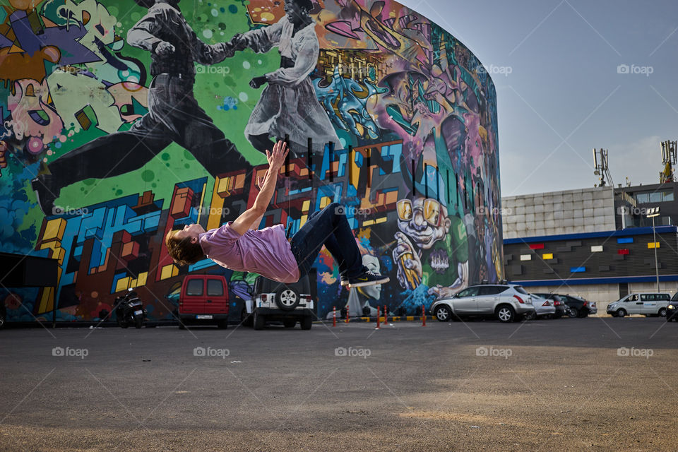 Man falling on ground in front of graffiti