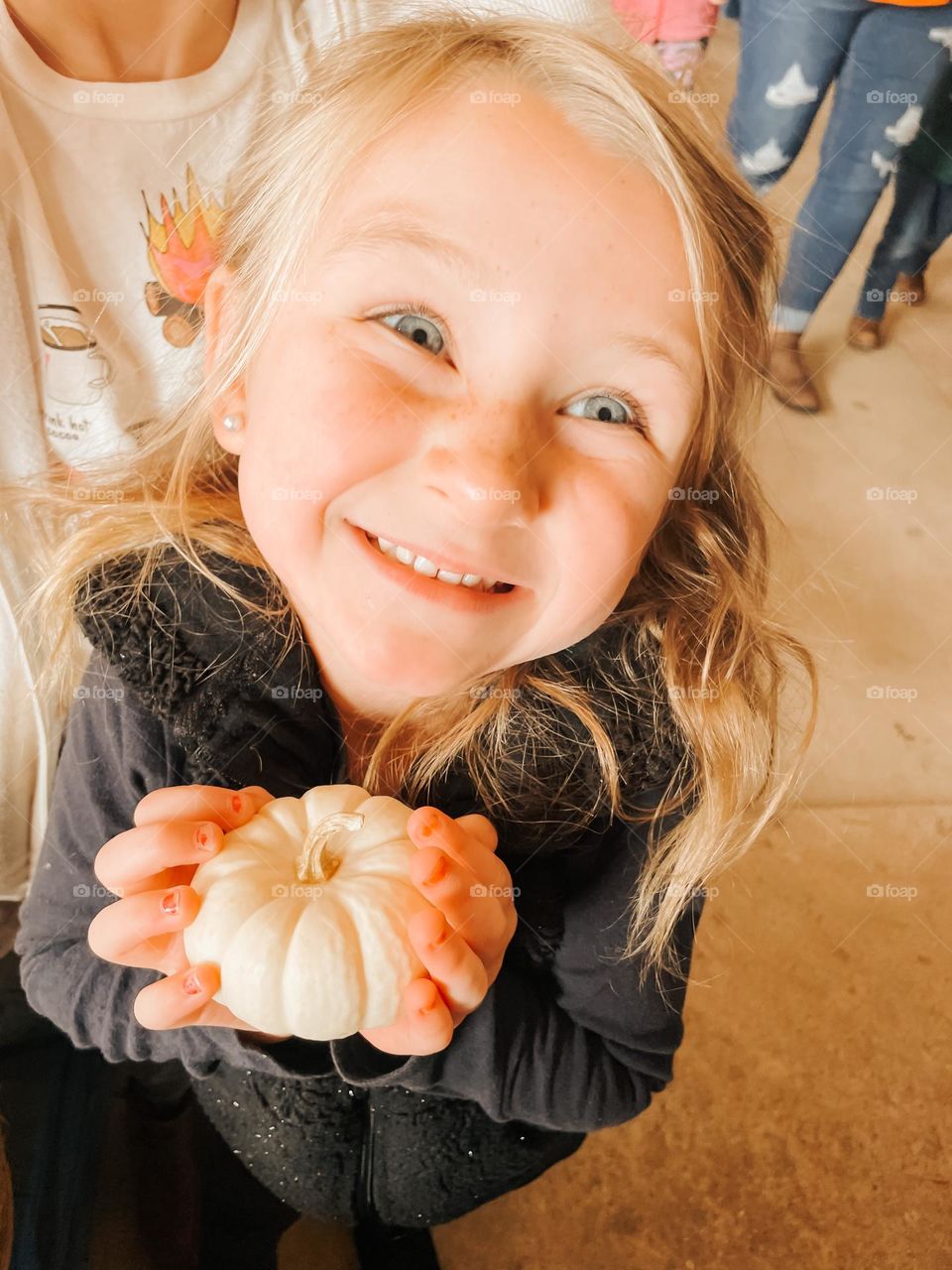 A girl smiling and holding a pumpkin 