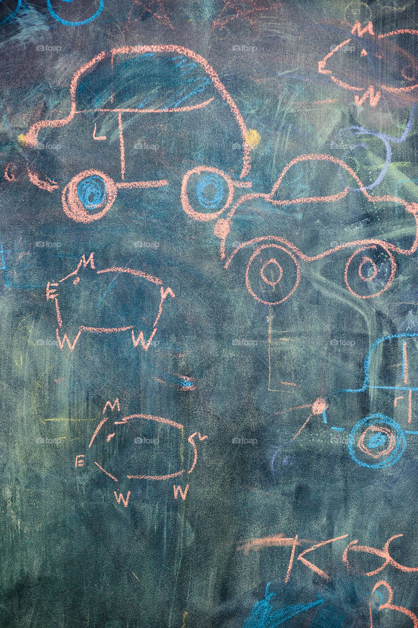 Childish colorful chalks drawings on blackboard depicting cars and characters