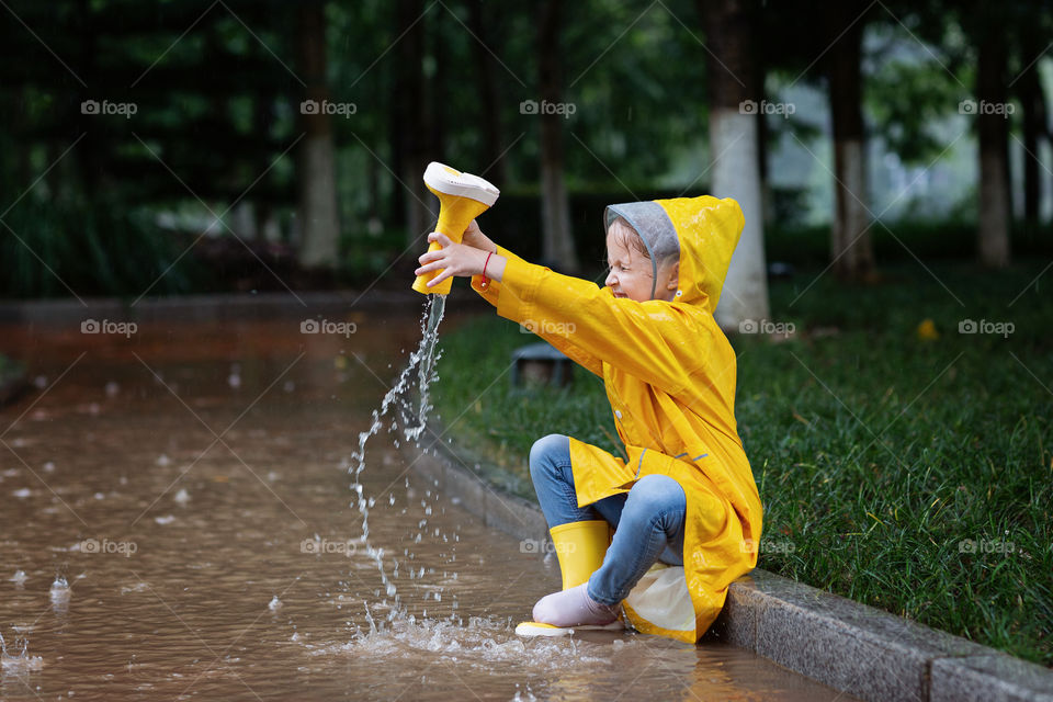 Little girl in yellow raincoat outdoor 