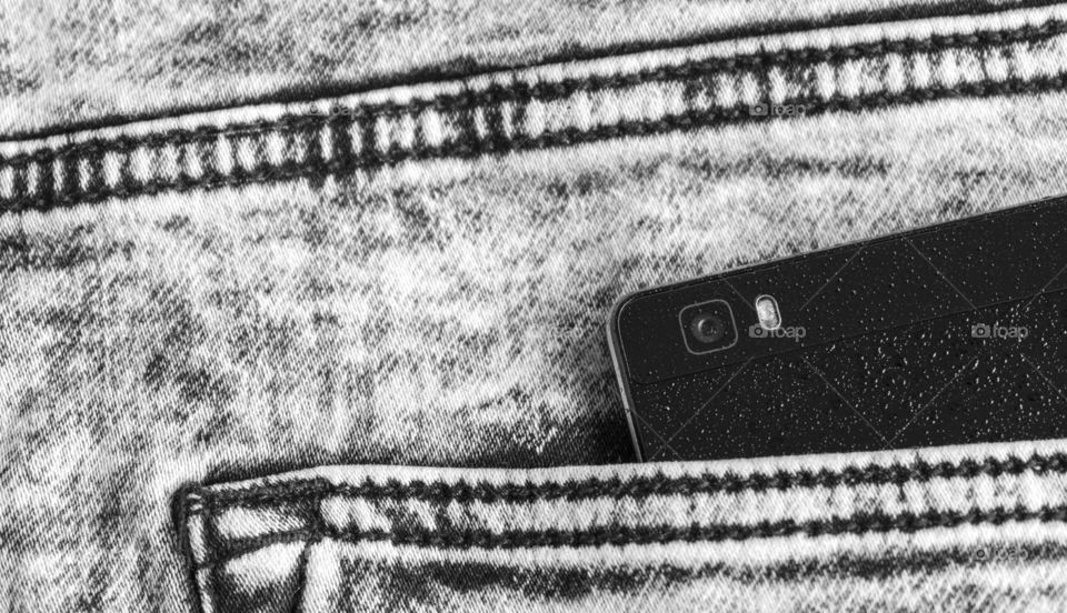 Black smartphone on jeans poket.Cell phone camera close up