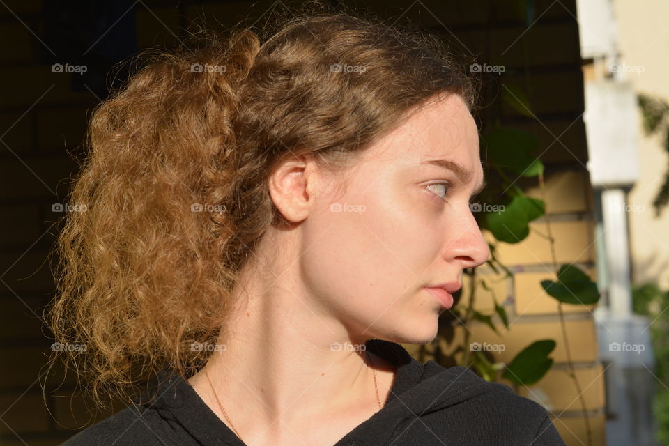 brunette girl beautiful portrait close up in sunlight brick wall background