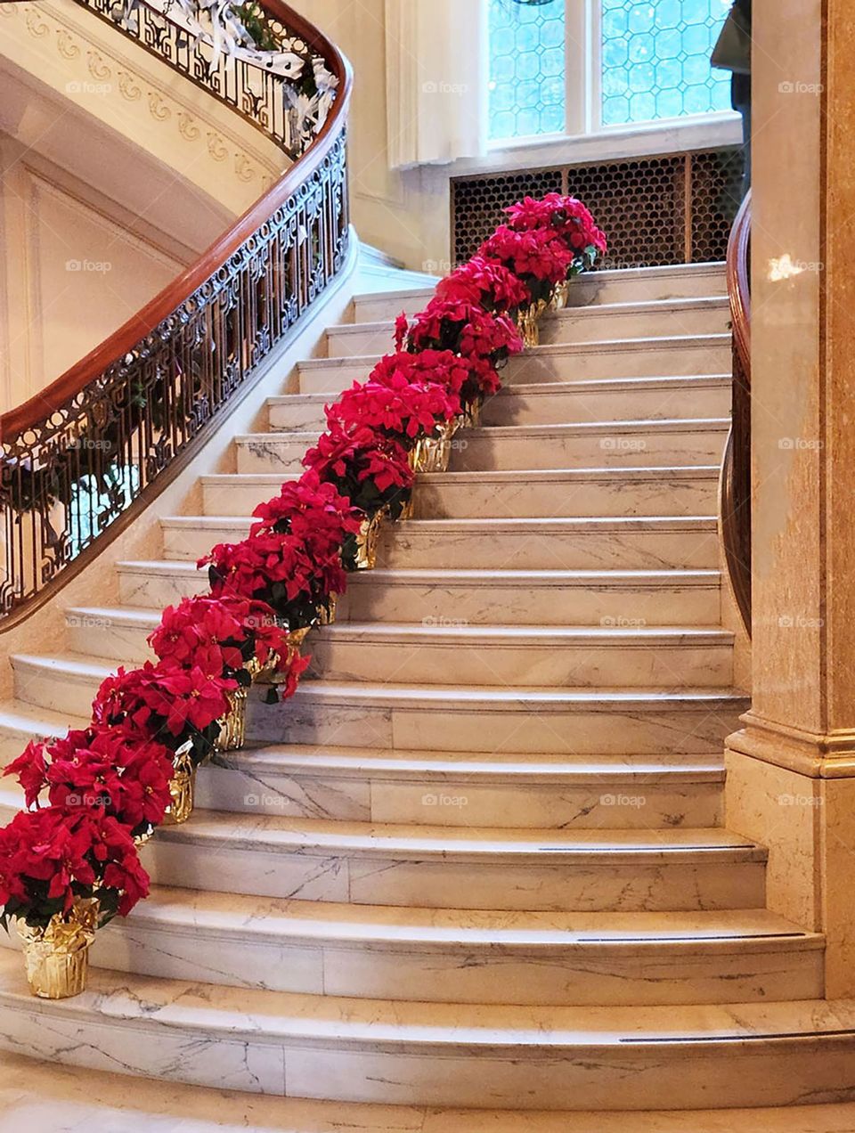 red poinsettias adorn an impressively grand staircase inside the Pittock mansion during the holiday season