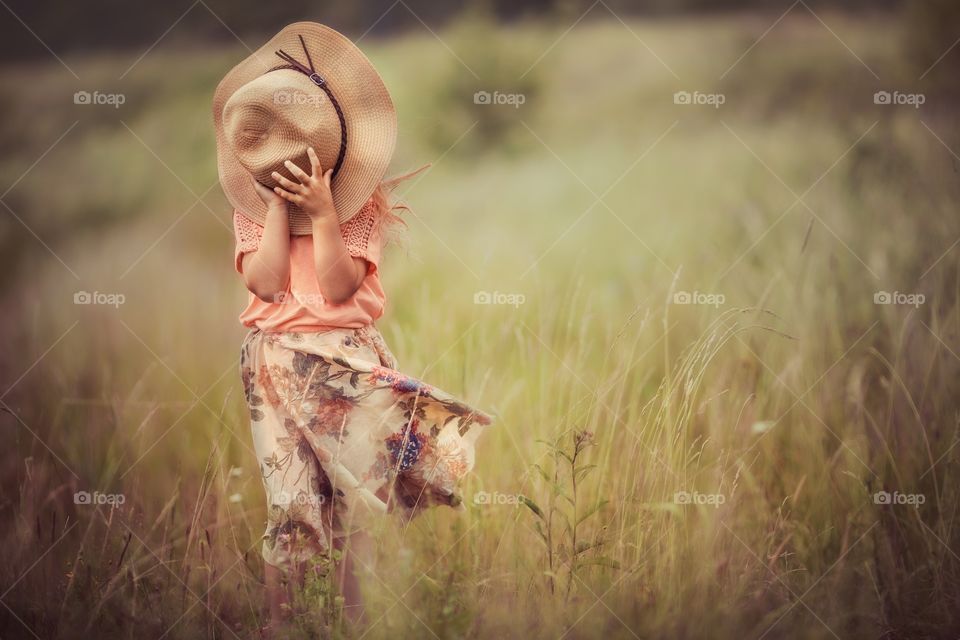 Little girl with a hat in a meadow