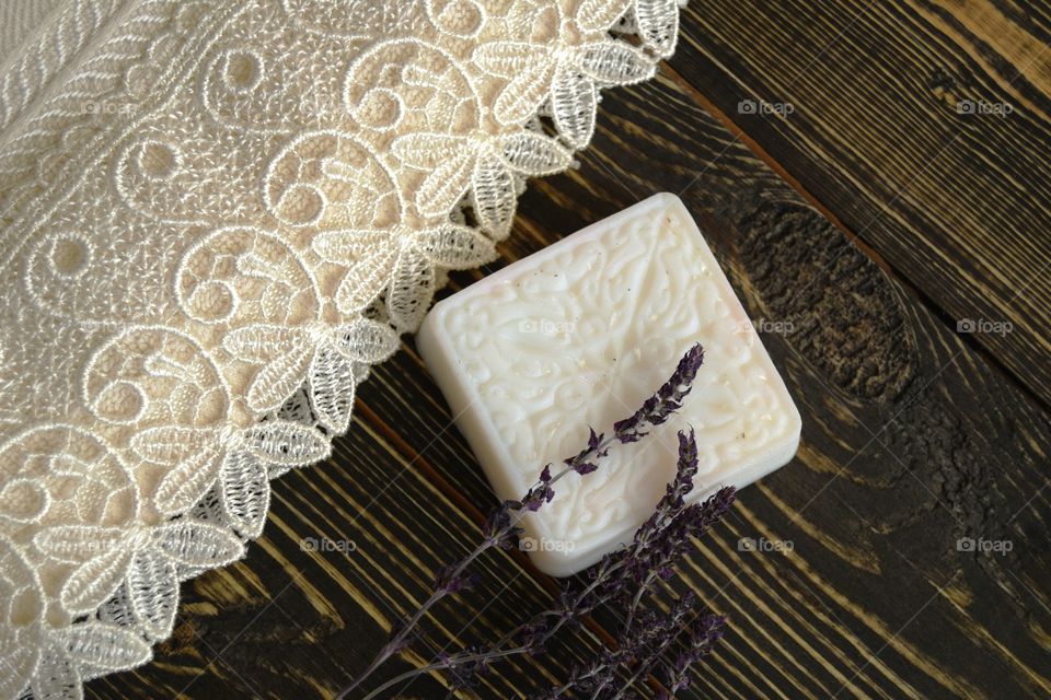 Soap with herbs and towel on wooden background 
