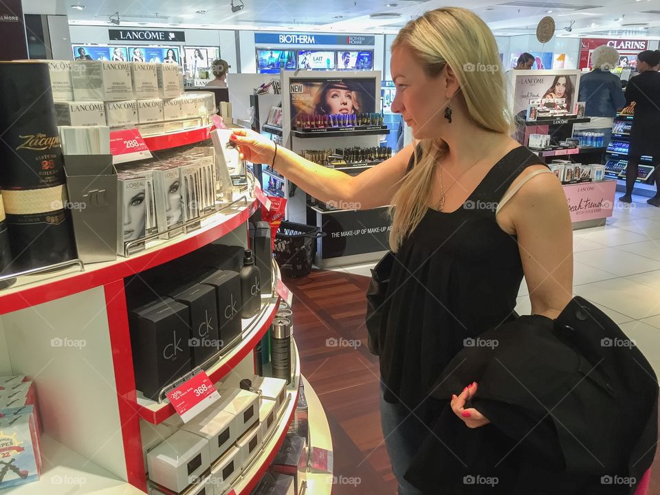 Young woman in her 30 years is smells perfume in a Taxfree shop at Copenhagen airport in Denmark.