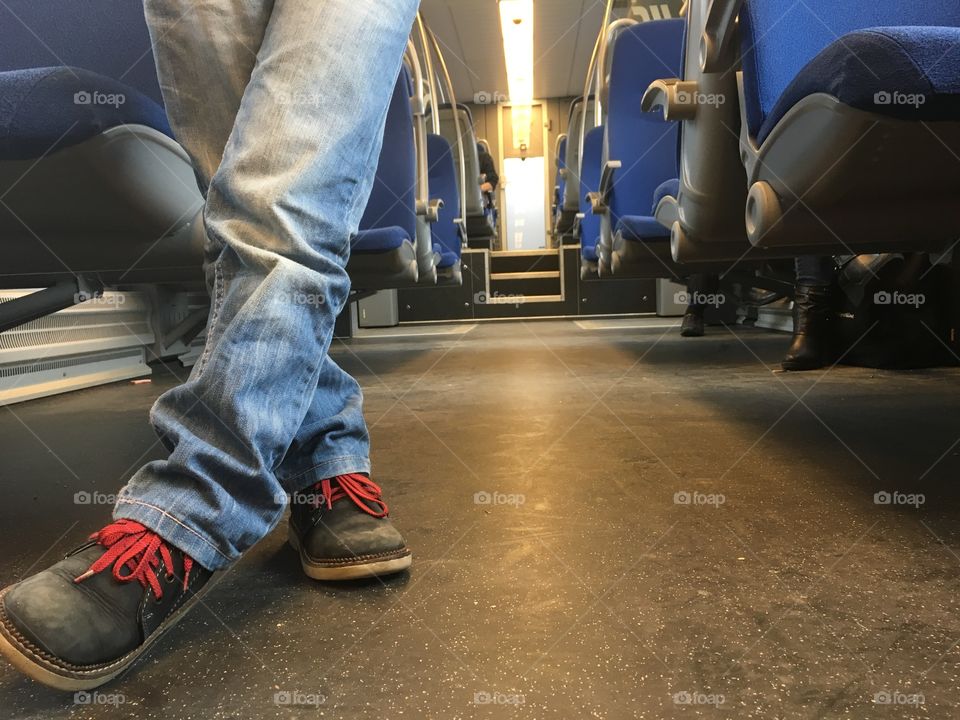 Child in jeans standing with legs crossed ina train