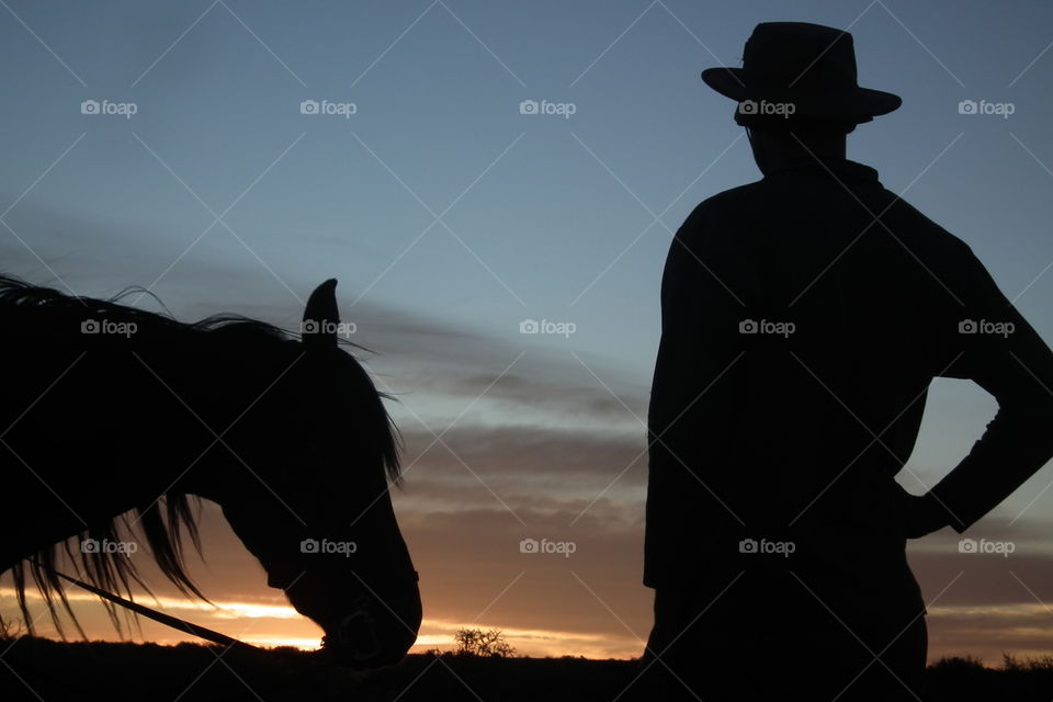 Horse rider taking a break to enjoy the beautiful sunset. Both of them enjoying the view!