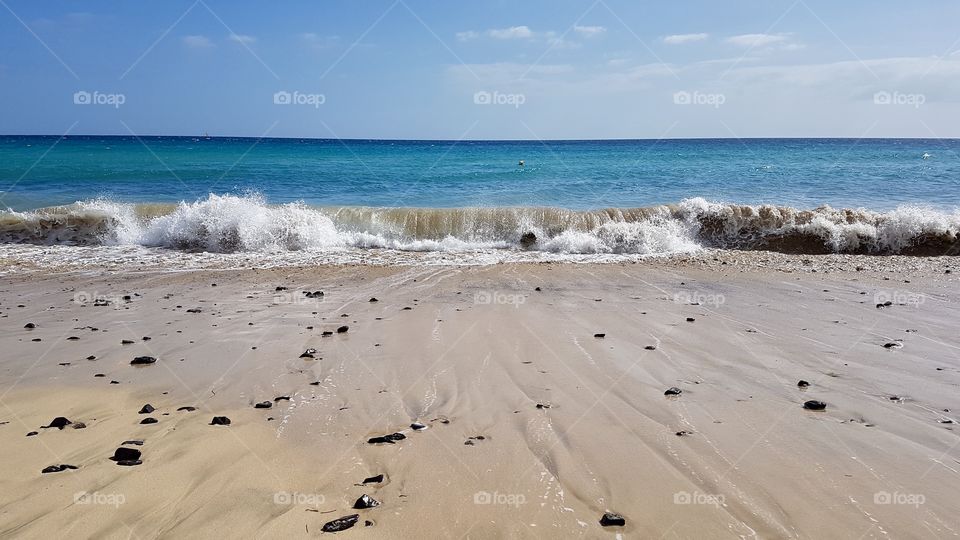 Sandy beach and waves in sunny weather, vacation in Fuerteventura Canary Islands Spain - fin sandstrand och vågor i soligt väder på Kanarieöarna Spanien