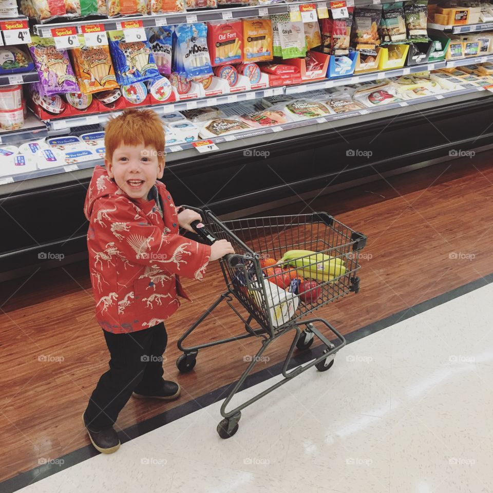 Toddler having fun grocery shopping. 