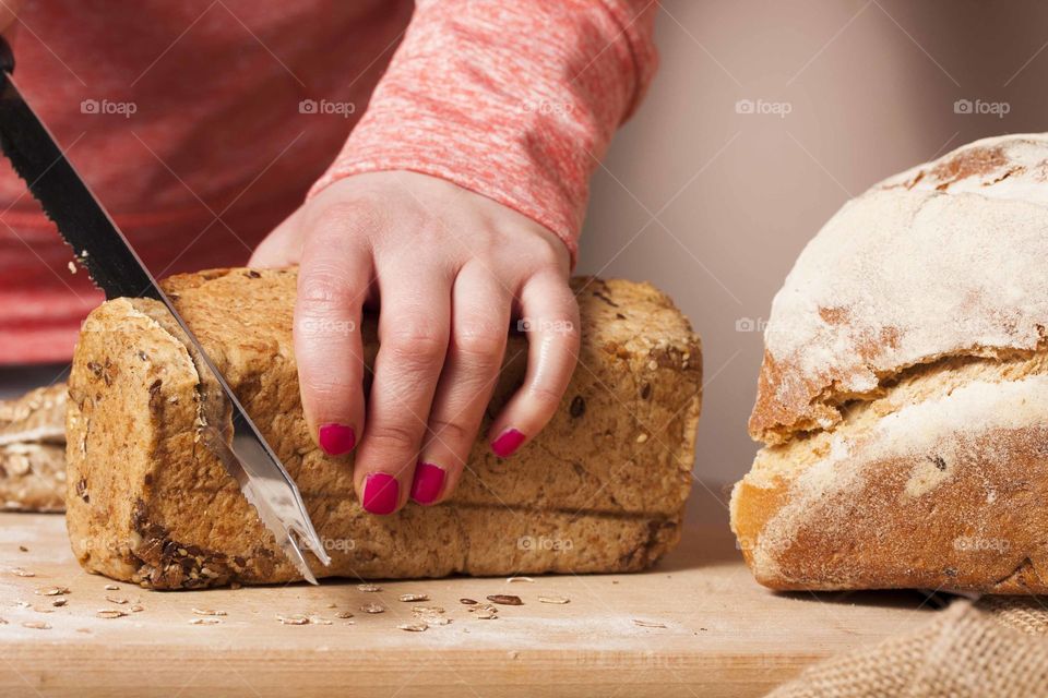 Woman slicing a mixed grain loaf of bread
