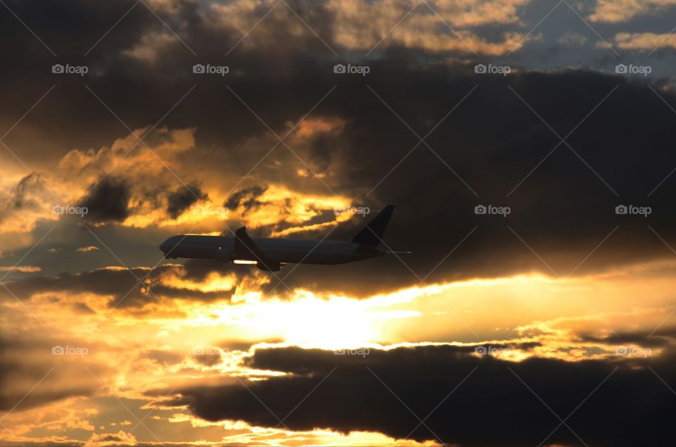 A commercial airliner crosses the face of an amazing sunset in the skies above Newark airport.
