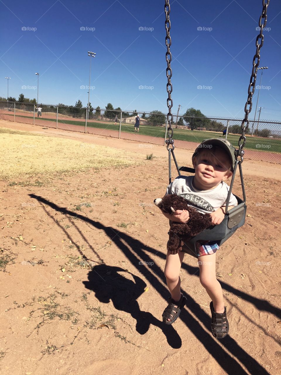 Toddler boy in infant swing on playground
