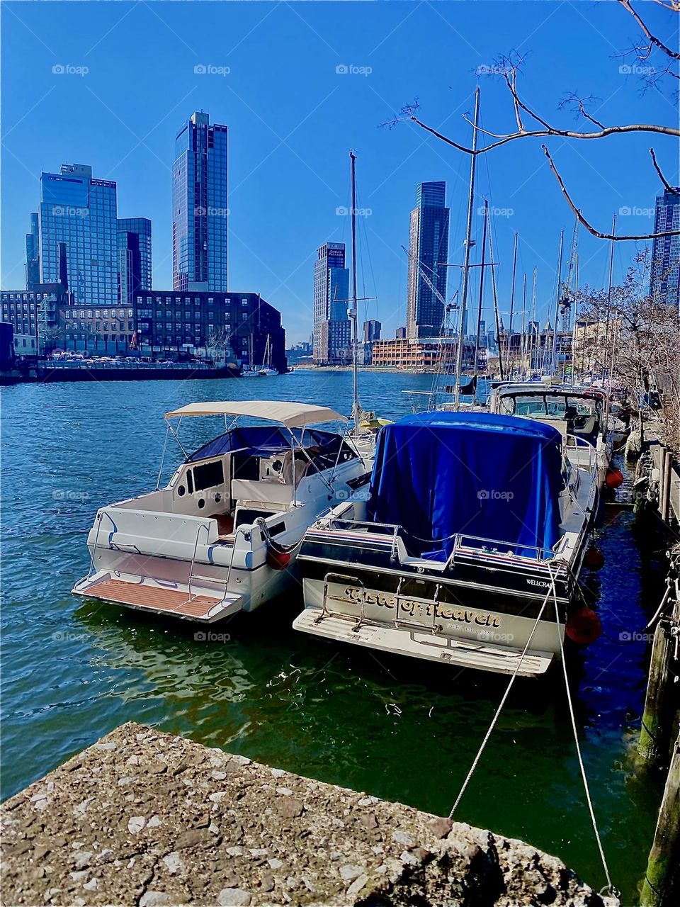 This is an idyllic setting: Two boats side by side in the “East River” at “Newtown Creek” in Long Island City, Queens, NY. The ocean is literally sparkling in a deep turquoise blue color today. 2023. Hypnotic Productions