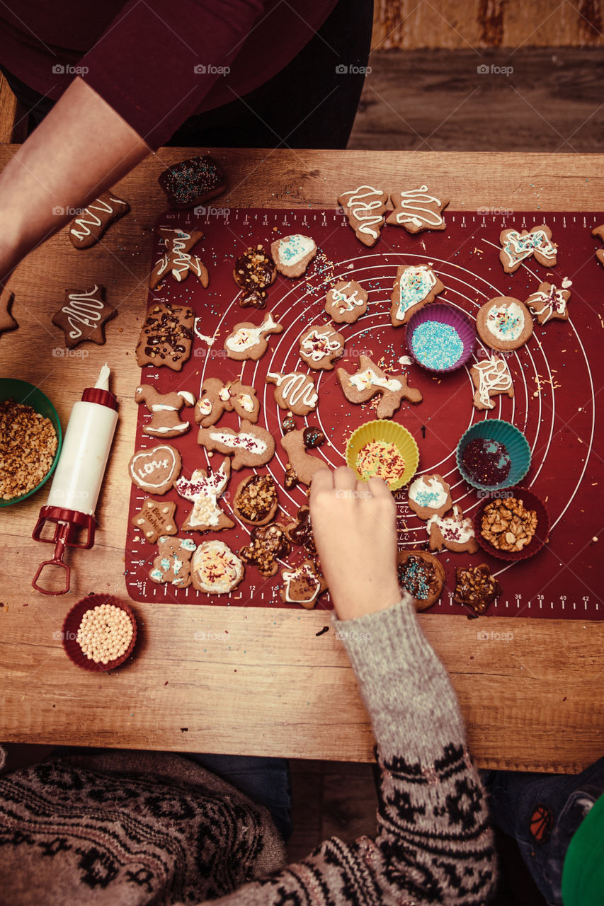 Baking Christmas cookies. Christmas gingerbread cookies in many shapes decorated with colorful frosting, sprinkle, icing, chocolate coating, toppers, put on table. Baking traditional cookies. Family celebrating Christmas. Baking at home