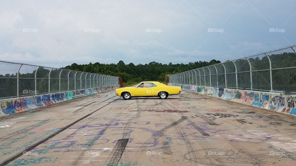 Yellow gto on bridge with graffiti