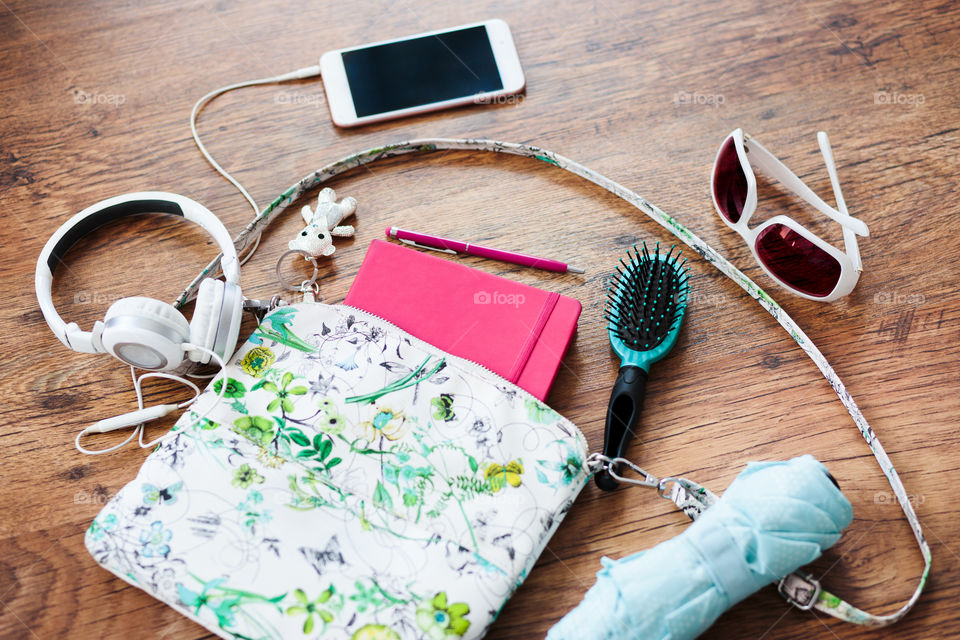 Smartphone sunglasses headphones and other things pulled out of handbag put on a table