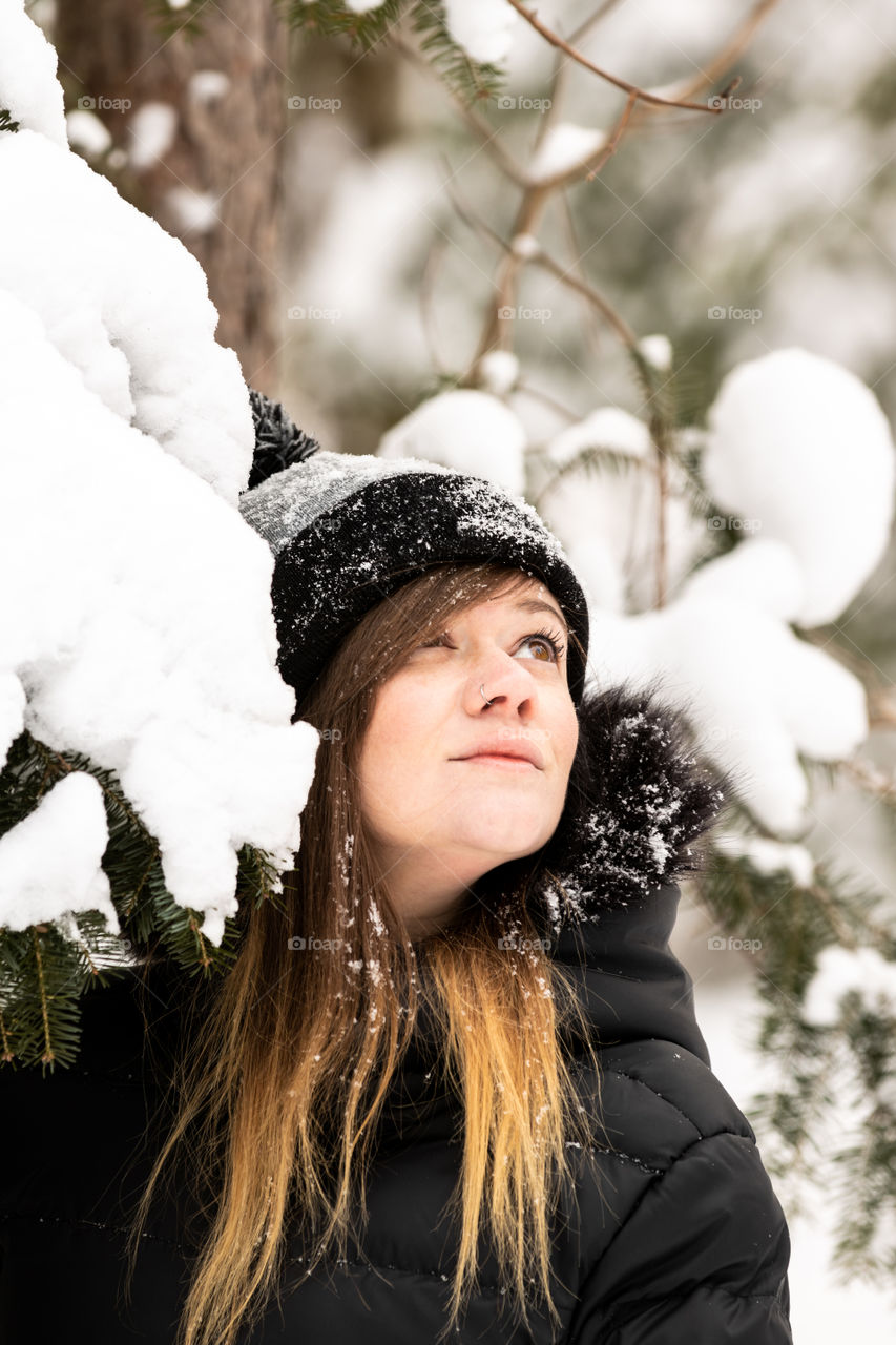 Young attractive female standing outside looking away in a snow covered winter wonderland scene. 