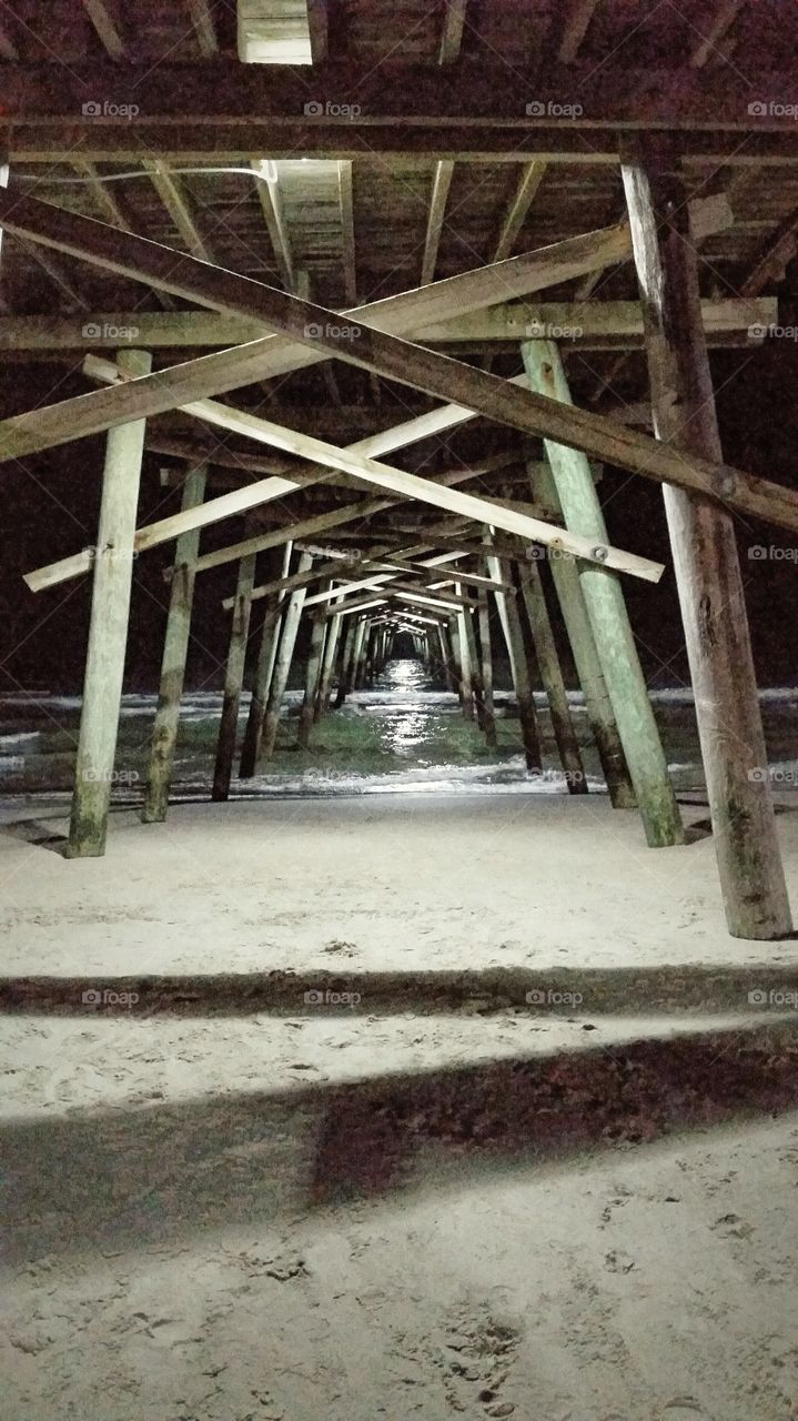 Under the Pier. This hallway of sand and water light a path out to the sea while holding up the pier.