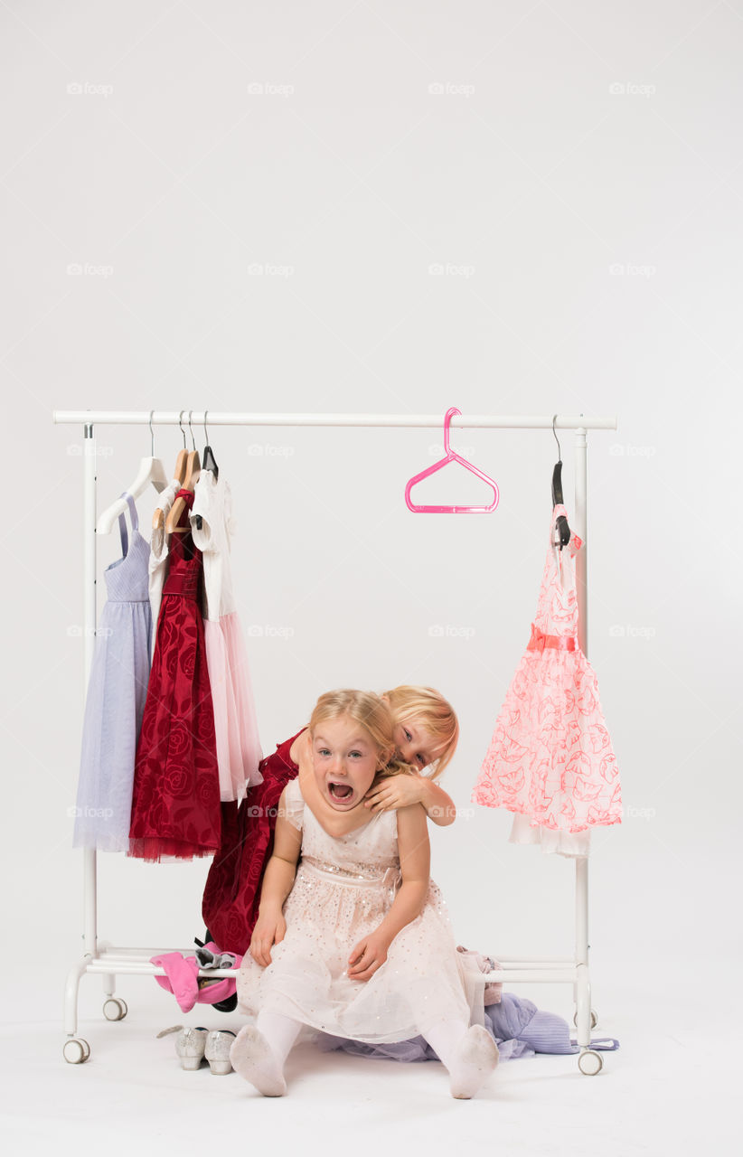 Two cute sisters is posing and playing with clothes and having fun.