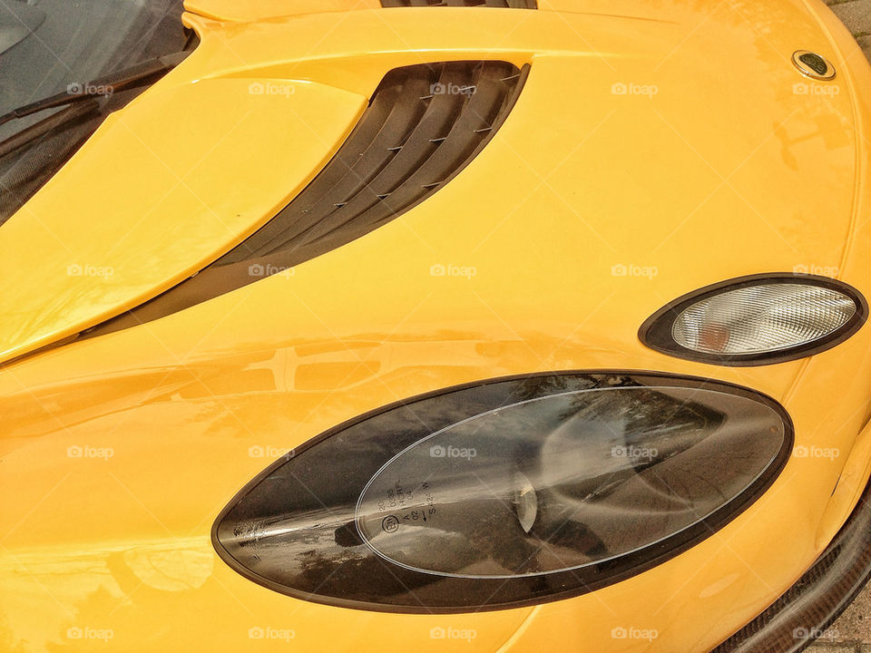 Close up detail of polished yellow hood and headlight of exotic Lotus