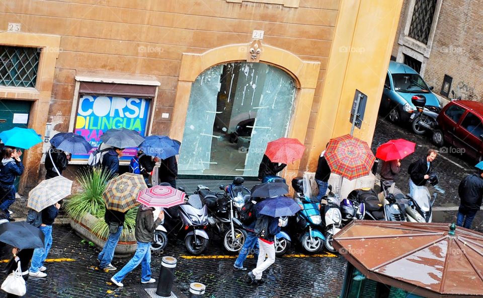 Colors in the rain. Brightly colored umbrellas shield a group of tourists along a Roman street 