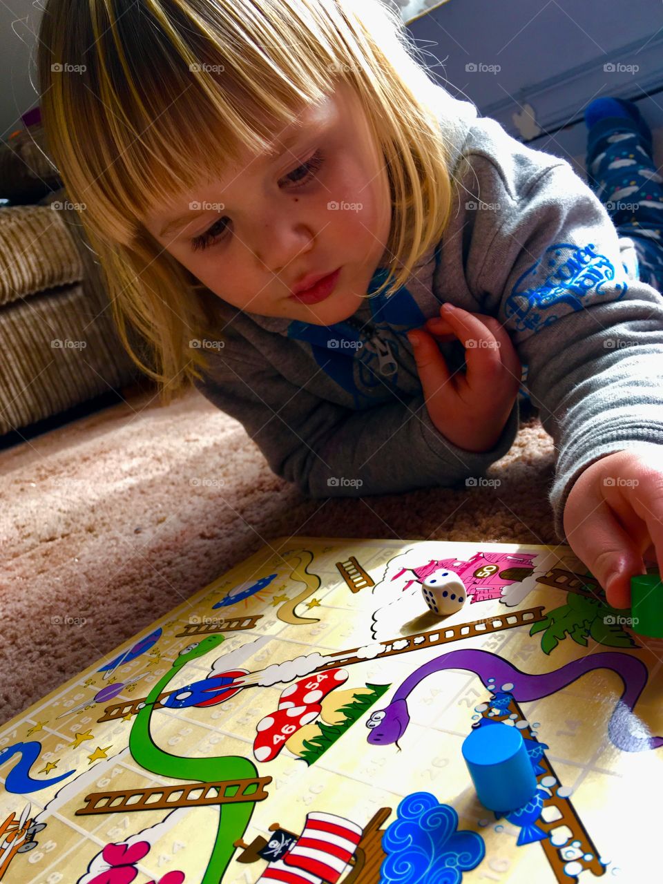 Face of a child and his favourite game. He loves counting when playing Snakes and Ladders 