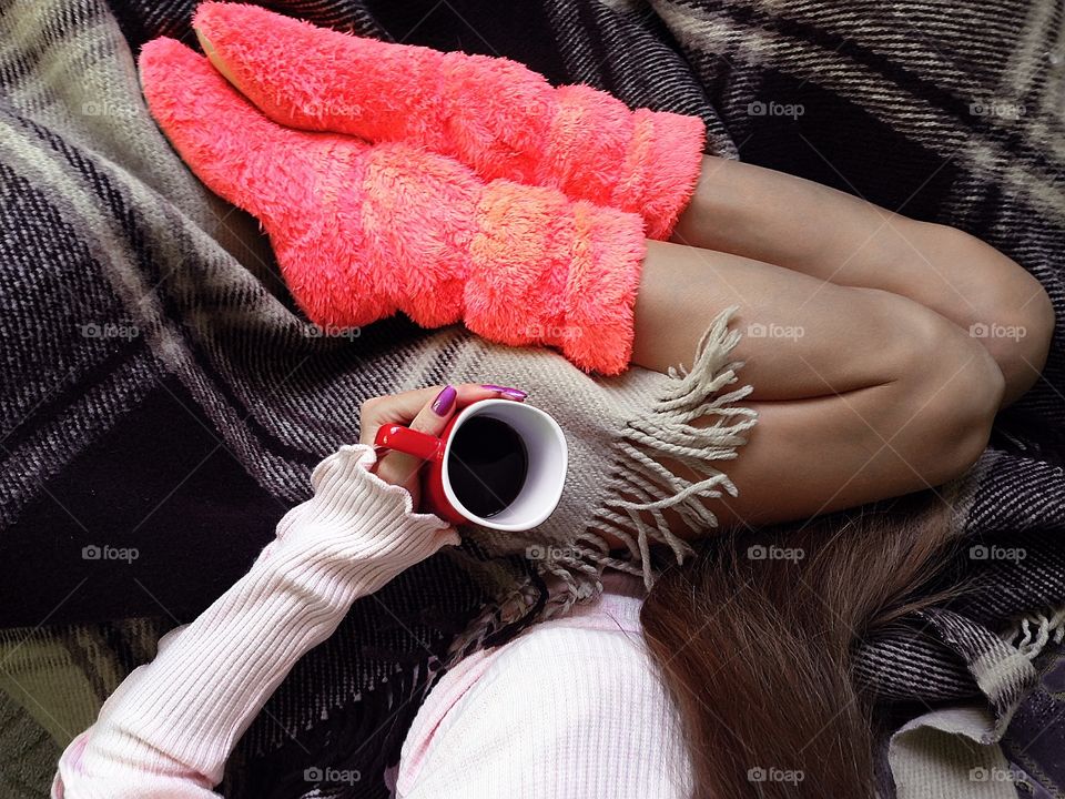 Young woman cozy snuggling in blanket in bed with a cup of coffee 