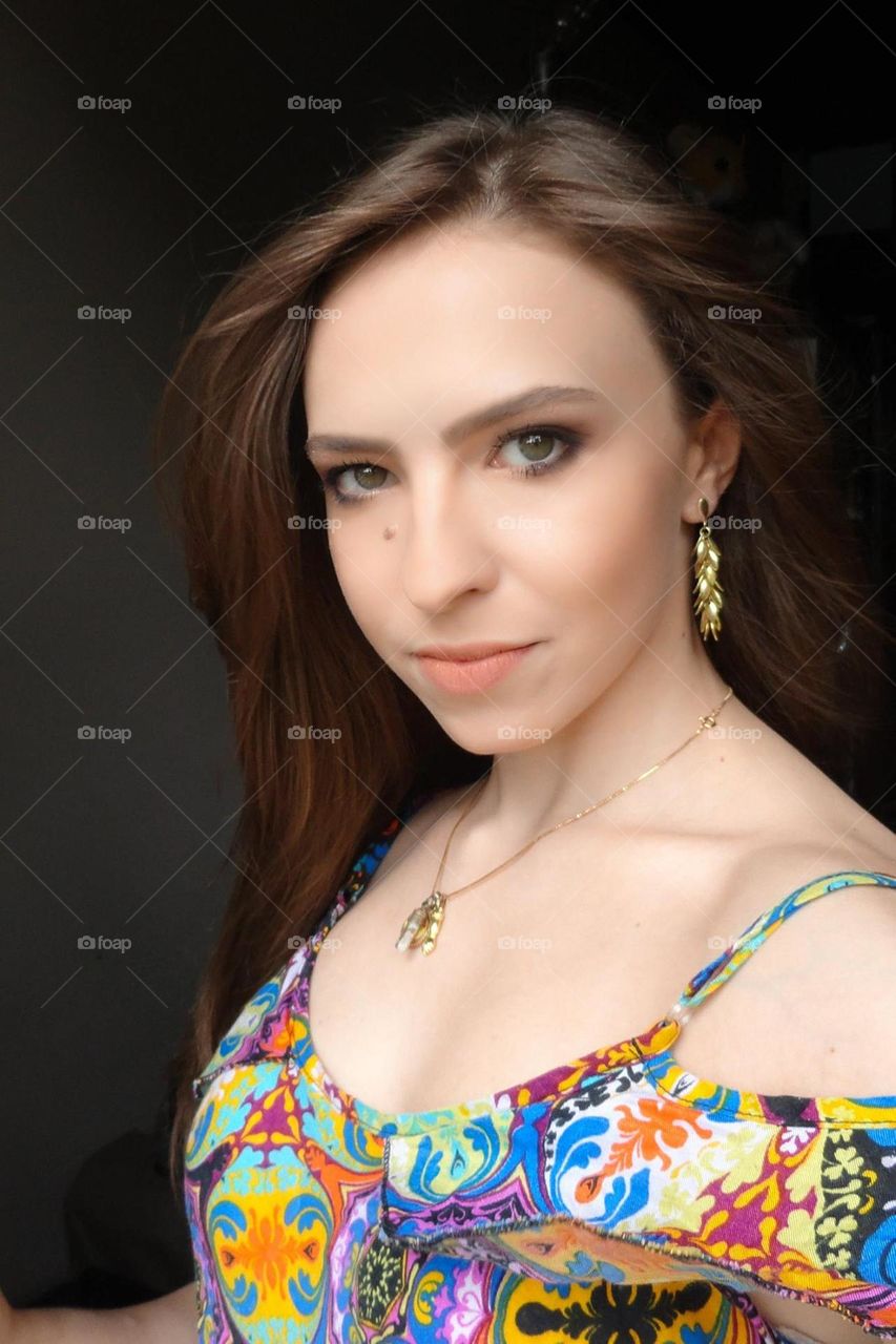Selfie of a green eyed brazilian woman with dark blonde flowing hair and colorful shirt