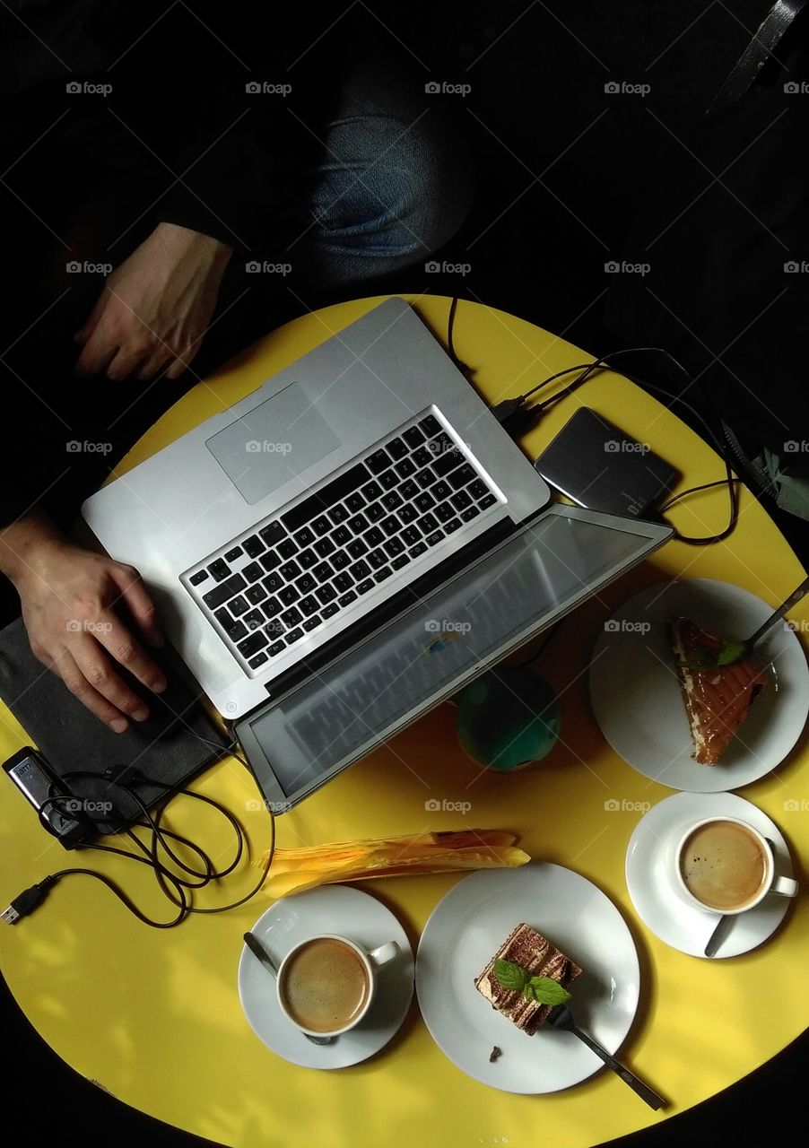 Top view of man working on his laptop in cafe.