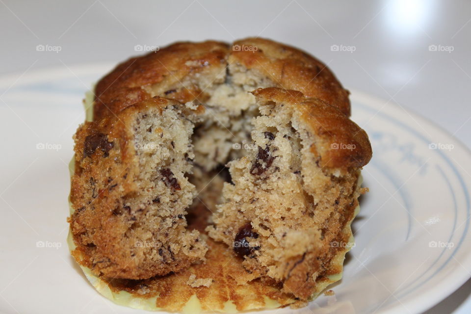 homemade banana muffin with raisins and cranberries on a decorative plate.