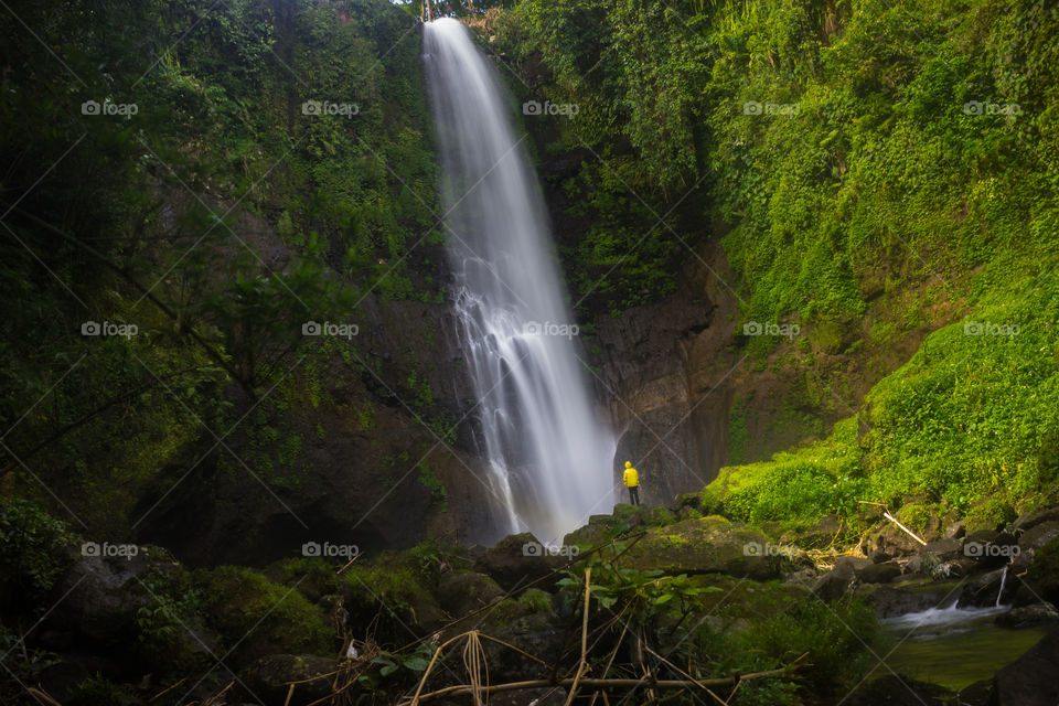 huge waterfall and man with yellow raincoat
