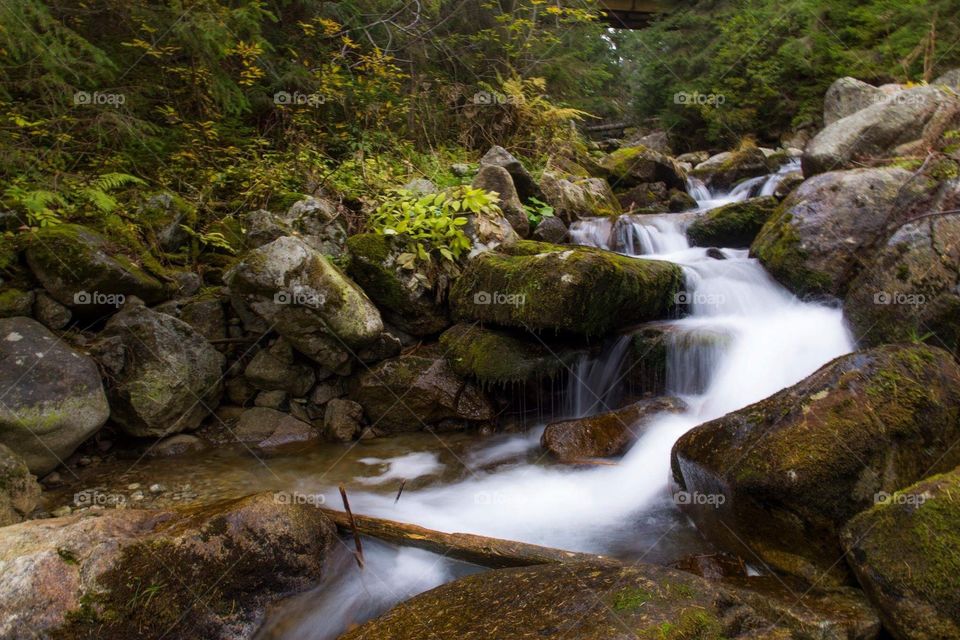 Polish mountains stream with waterfalls captured in a long exposure photograph.