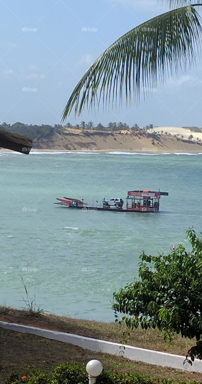 Ferry crossing a car over in Tibau do Sul, RN, Brazil. These go to the sand dunes on tours that can be seen in the background