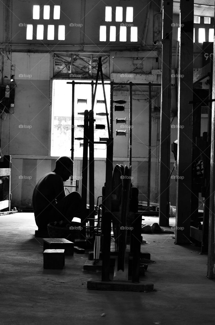 Man working on  Weaving machine at a 
Mandalay silk factory 


