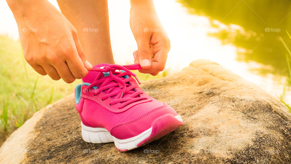 Running shoes. Female athlete tying laces for jogging on road Running shoes. Female athlete tying laces for jogging on road